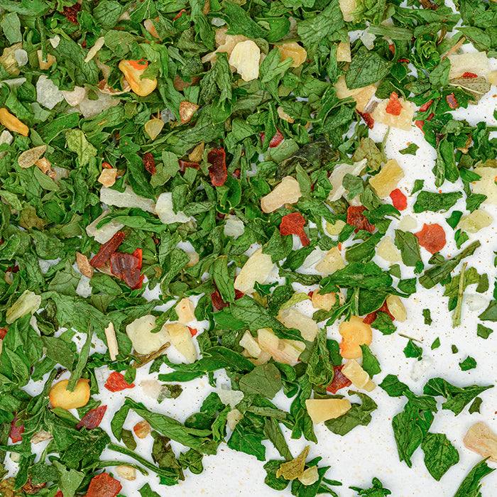 A vibrant blend of dried parsley, red bell pepper, and yellow onion—Whole Spice Inc.’s Chimichurri Seasoning—adds bold flavor to grilled meats, shown sprinkled across a white surface.