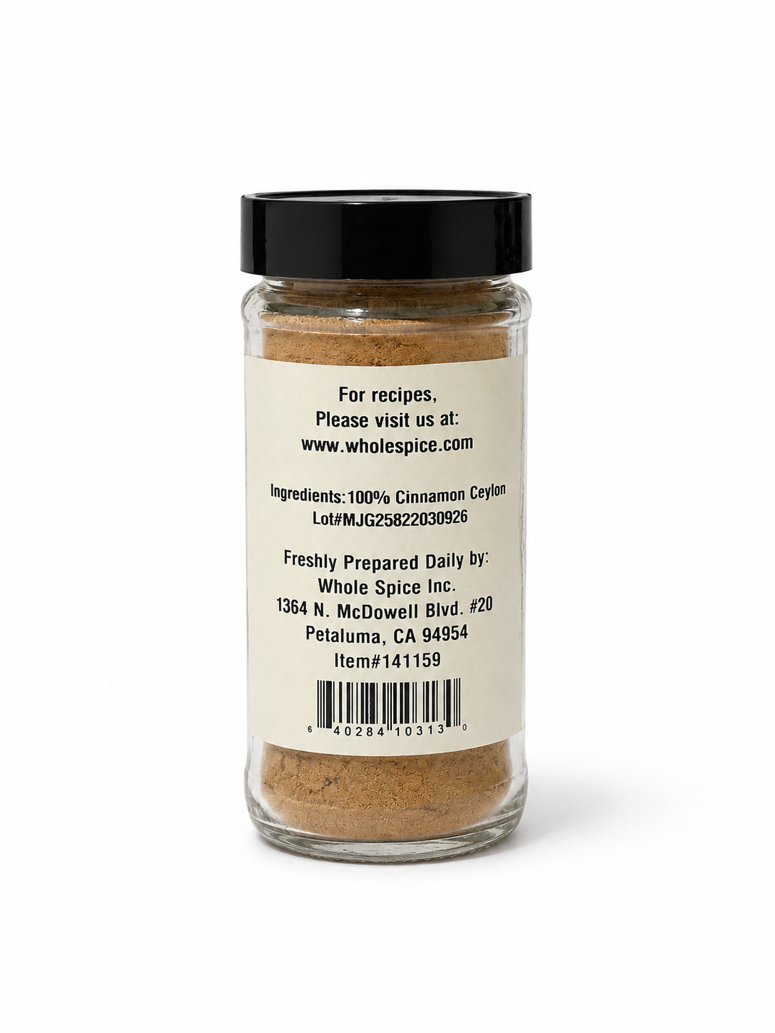 A transparent jar of Cinnamon Powder Ceylon by Whole Spice Inc., topped with a black lid, displays a white back label featuring the ingredients—100% Ceylon cinnamon, recognized for its anti-inflammatory qualities—alongside the company’s contact information.