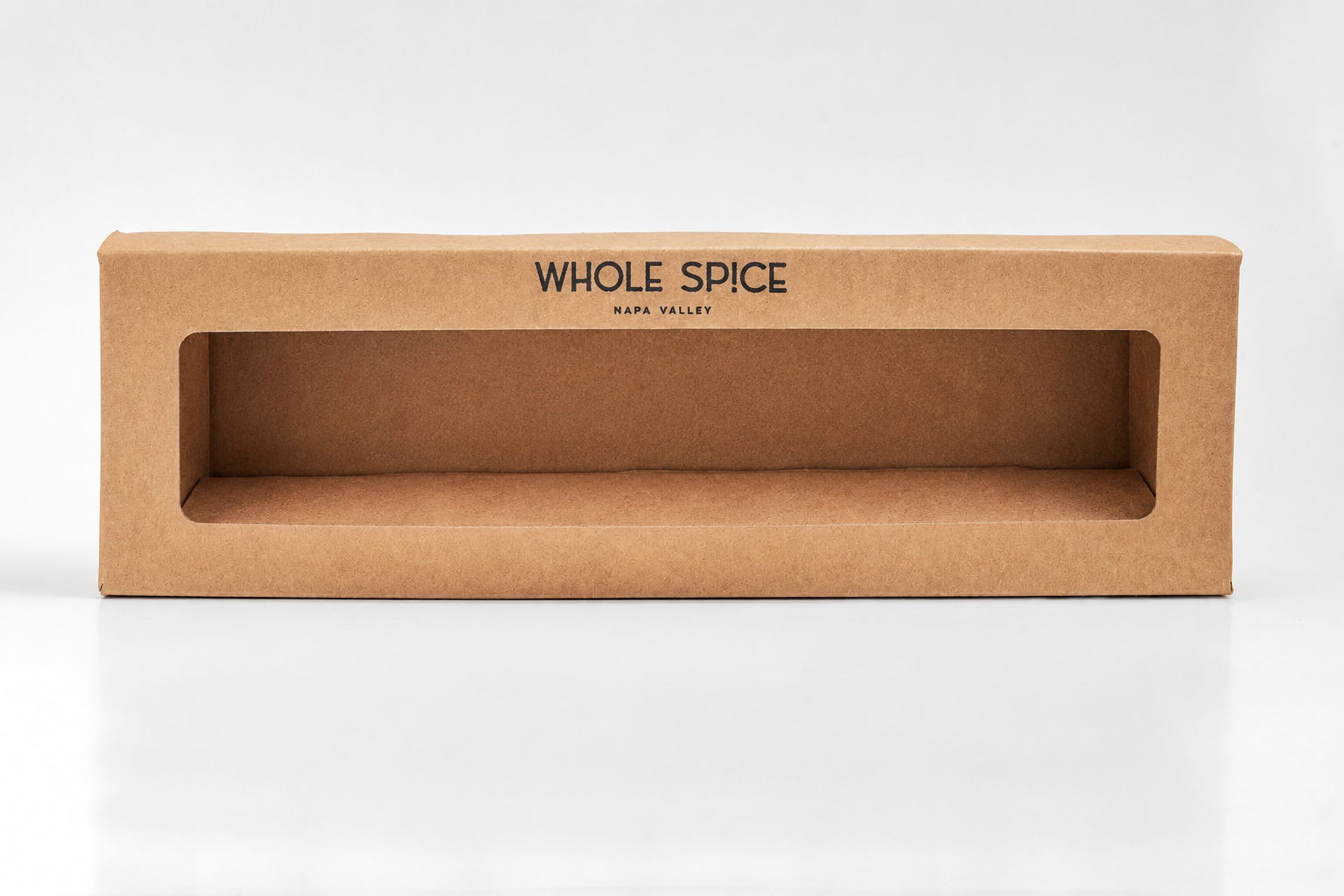 A rectangular brown Build Your Own Gift Box from Whole Spice, Inc. with a large clear window and branding on top is displayed empty against a white background, ready to hold spice jars for gifting or display.