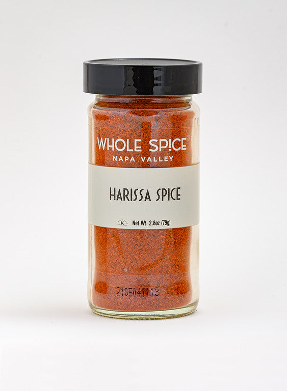 A 2.8 oz (79g) glass jar of Whole Spice Inc. Harissa Spice, featuring a black lid and a label with the brand name, spice name, and net weight. Contains a spicy chili blend.