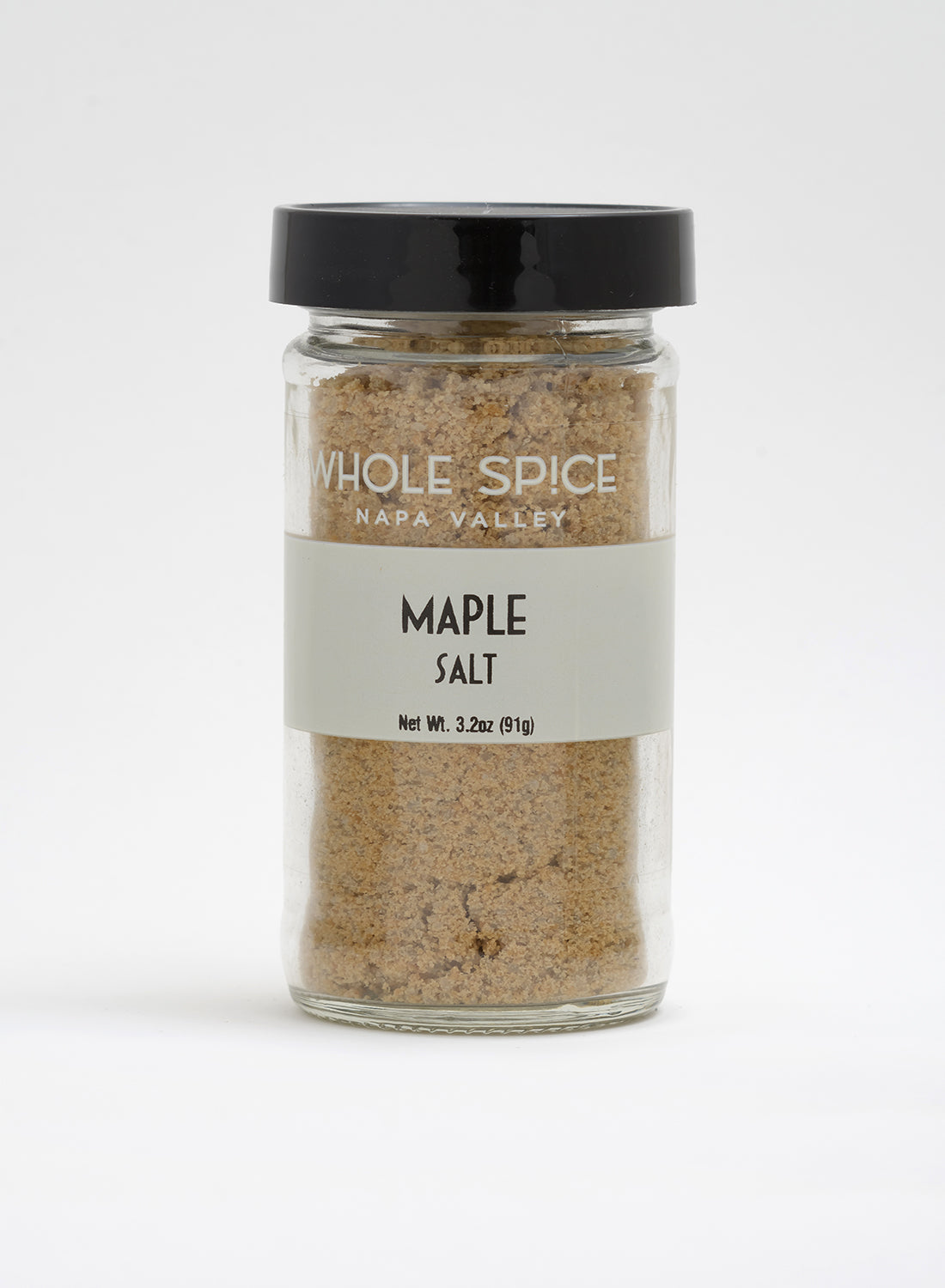 A clear glass jar with a black lid holds Whole Spice Inc. Maple Salt, a light brown granulated gourmet seasoning made from pure maple syrup. Net weight: 3.2 oz (91g).