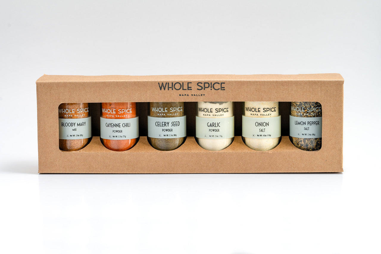 The Whole Spice Bloody Mary Gift Set by Whole Spice Inc. comes in a brown box with a clear window, featuring six seasoning jars: Bloody Mary, Cayenne Chili, Celery Seed Powder, Garlic Powder, Onion Salt, and Lemon Pepper.