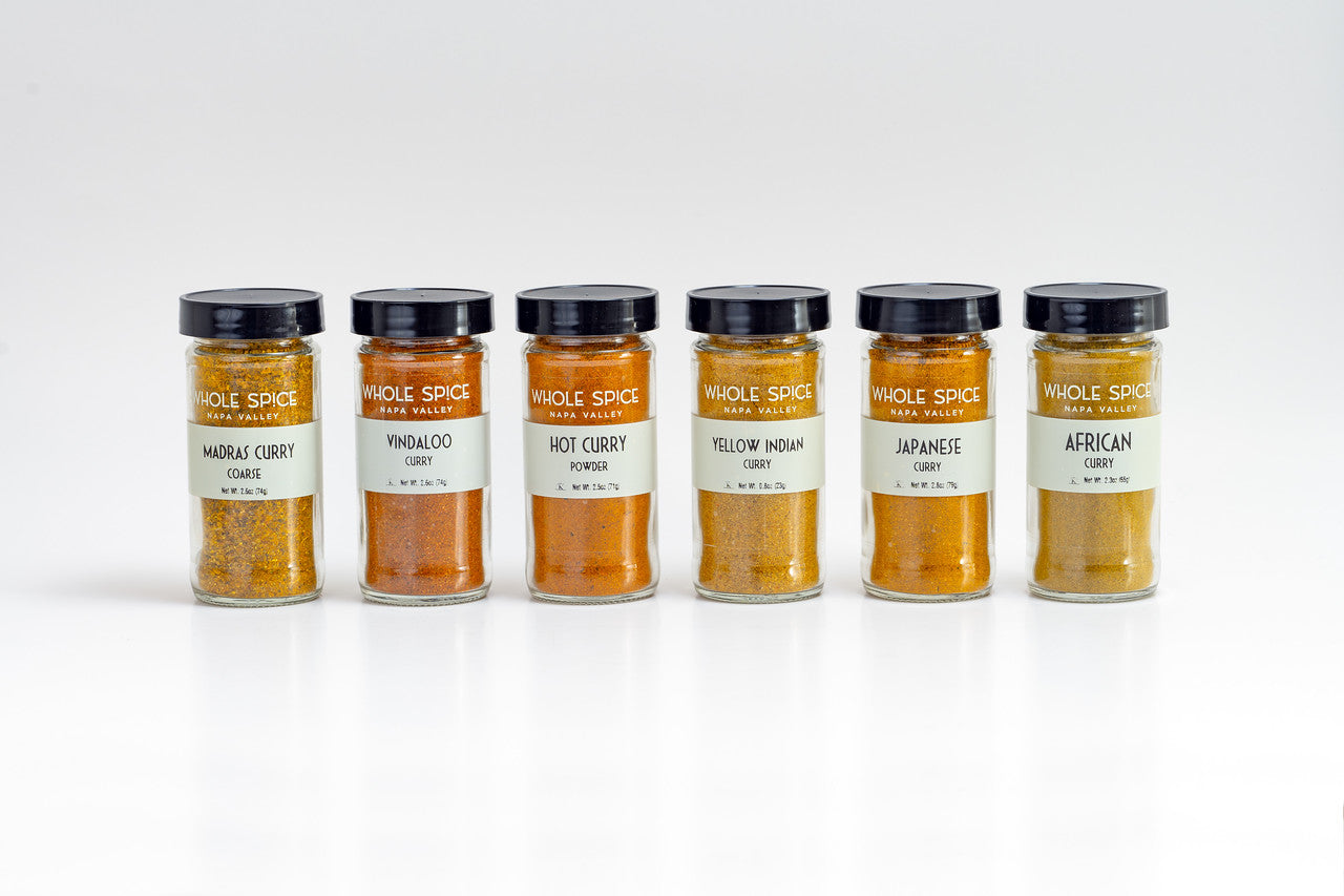 The Whole Spice Inc. Curry Gift Set features six jars—Madras, Vindaloo, Hot, Yellow Indian, Japanese, and African Curry—lined up on a white background with vibrant labels.