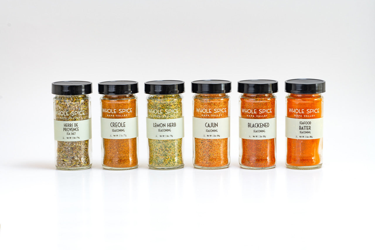The Whole Spice Inc. Grilling Fish & Seafood Spice Set includes six seasonings—Herbes de Provence, Creole, Lemon Herb, Cajun, Blackened, and Seafood Batter—perfect for grilling fish or enhancing seafood dishes. Jars arranged on a white background.