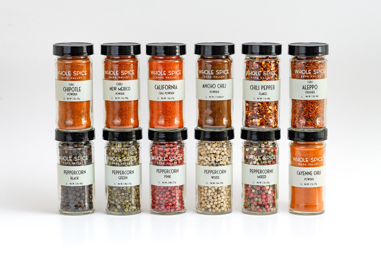 The Whole Spice Inc. Peppers and Chili Jar Set features 12 jars, including chili powders, crushed chilies, and peppercorn mixes—arranged in two rows against a white background—a perfect spice gift set for any kitchen.
