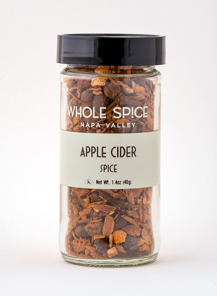 A glass jar with a black lid labeled Whole Spice Inc. Apple Cider Spice, filled with small brown spice pieces ideal for hot mulled cider. Net weight: 1.4 oz (40g).