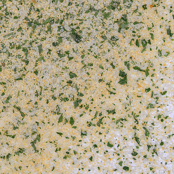 A close-up of Whole Spice Inc.'s Garlic & Parsley Sea Salt shows coarse salt, parsley flakes, and garlic granules—ideal for enhancing dipping oil or finishing dishes.