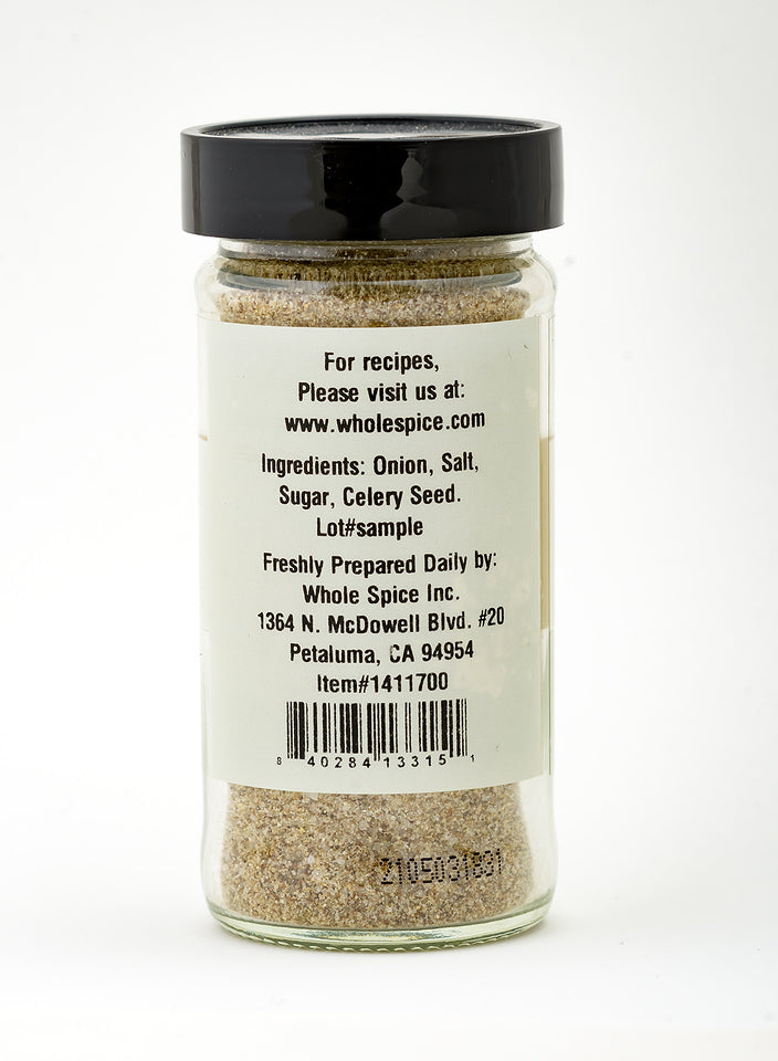 A clear spice jar with a black lid displays the Le Beau Monde blend by Whole Spice Inc., featuring onion, salt, sugar, and celery seed—perfect as a versatile seasoning for any dish.