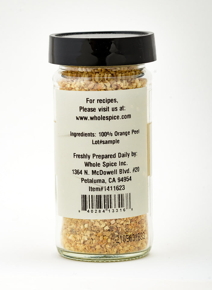 Orange Peel Granules by Whole Spice Inc. come in a clear jar with a black lid, providing vibrant citrus flavor from 100% orange peel. The label includes the company's details, address, and website for recipes.