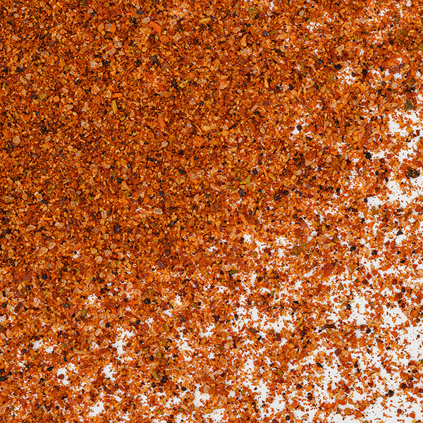 Close-up of a scattered pile of Whole Spice Inc. Taco Seasoning, an authentic Mexican blend of finely ground spices and herbs, on a white background.