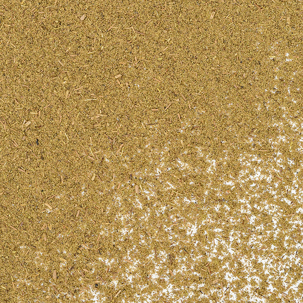 A close-up of Whole Spice Inc. Thyme Powder, a finely ground brownish-green herb, scattered unevenly on a white surface.
