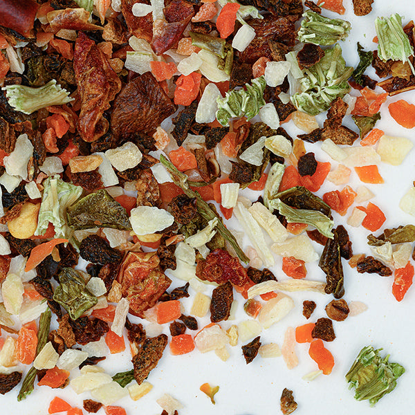 A close-up of Whole Spice Inc. Vegetable Flakes—dried carrots, onions, tomatoes, celery, and herbs—scattered on white background; ideal for salad dressings or adding robust flavor to soups.