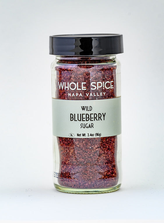 A 3.4 oz (96g) glass jar with a black lid labeled Whole Spice Inc. Wild Blueberry Sugar, filled with vibrant reddish-purple sugar, shown on a plain white background.