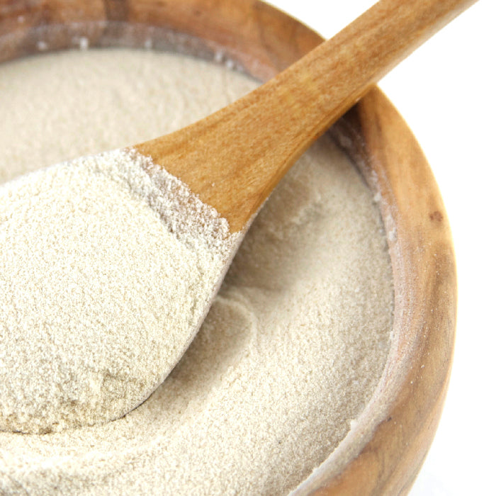 A wooden bowl filled with Whole Spice Inc. Agar Agar powder, a popular vegan thickening agent, with a wooden spoon inside holding a scoop of the off-white powder.