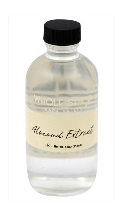 A 4 oz (118 ml) clear glass bottle of Whole Spice Inc. Almond Extract with a black screw cap, ideal for adding almond paste flavor to desserts.