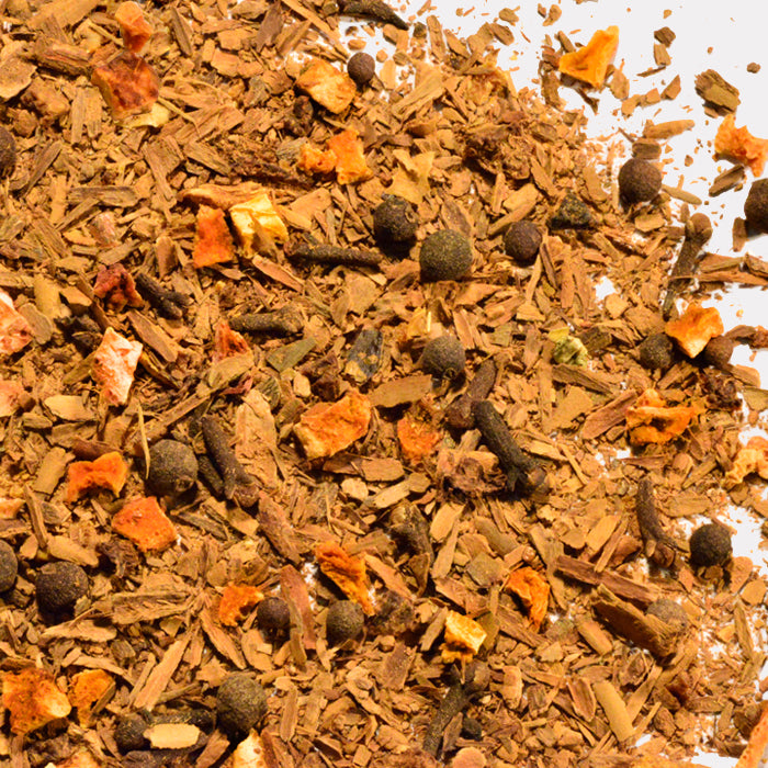 A close-up of Whole Spice Inc.'s Apple Cider Spice blend, featuring bark pieces, whole black peppercorns, cloves, and orange bits on a white surface—a seasonal favorite for hot mulled cider.