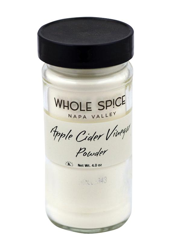 A glass jar with a black lid labeled “Whole Spice Inc. Apple Cider Vinegar Powder, Net Wt. 4.0 oz,” filled with white powder perfect for seasoning blends and adding tangy flavor to recipes.