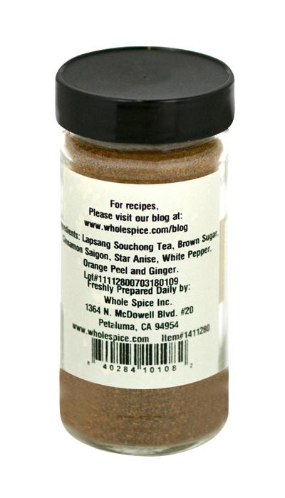 Whole Spice Inc. Asian Smoked Tea Rub comes in a clear glass jar with a black lid. This bold blend, infused with Lapsang Souchong tea and star anise, is perfect as an Asian tea marinade. The label lists ingredients and contact info.