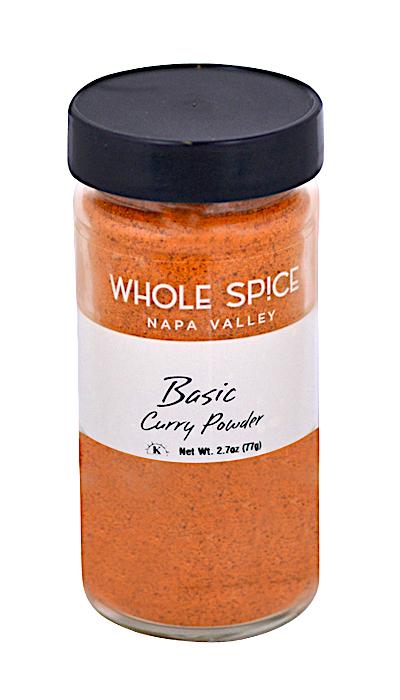 A clear jar with a black lid holds orange Basic Curry Powder from Whole Spice Inc., Net Wt. 2.7oz (77g)—perfect for mild curries or Indian dishes.