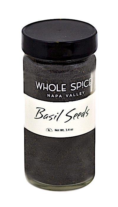 A clear glass jar with a black lid labeled Whole Spice Inc. Basil Seeds contains dark basil seeds, also called tukmaria or sabja seeds, with a net weight of 3.4 oz.