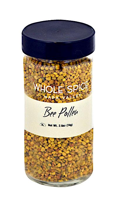 A clear glass jar with a black lid contains yellow and orange bee pollen granules. The label reads Whole Spice Inc. Bee Pollen, Net Wt. 2.6oz (74g)—a natural superfood.