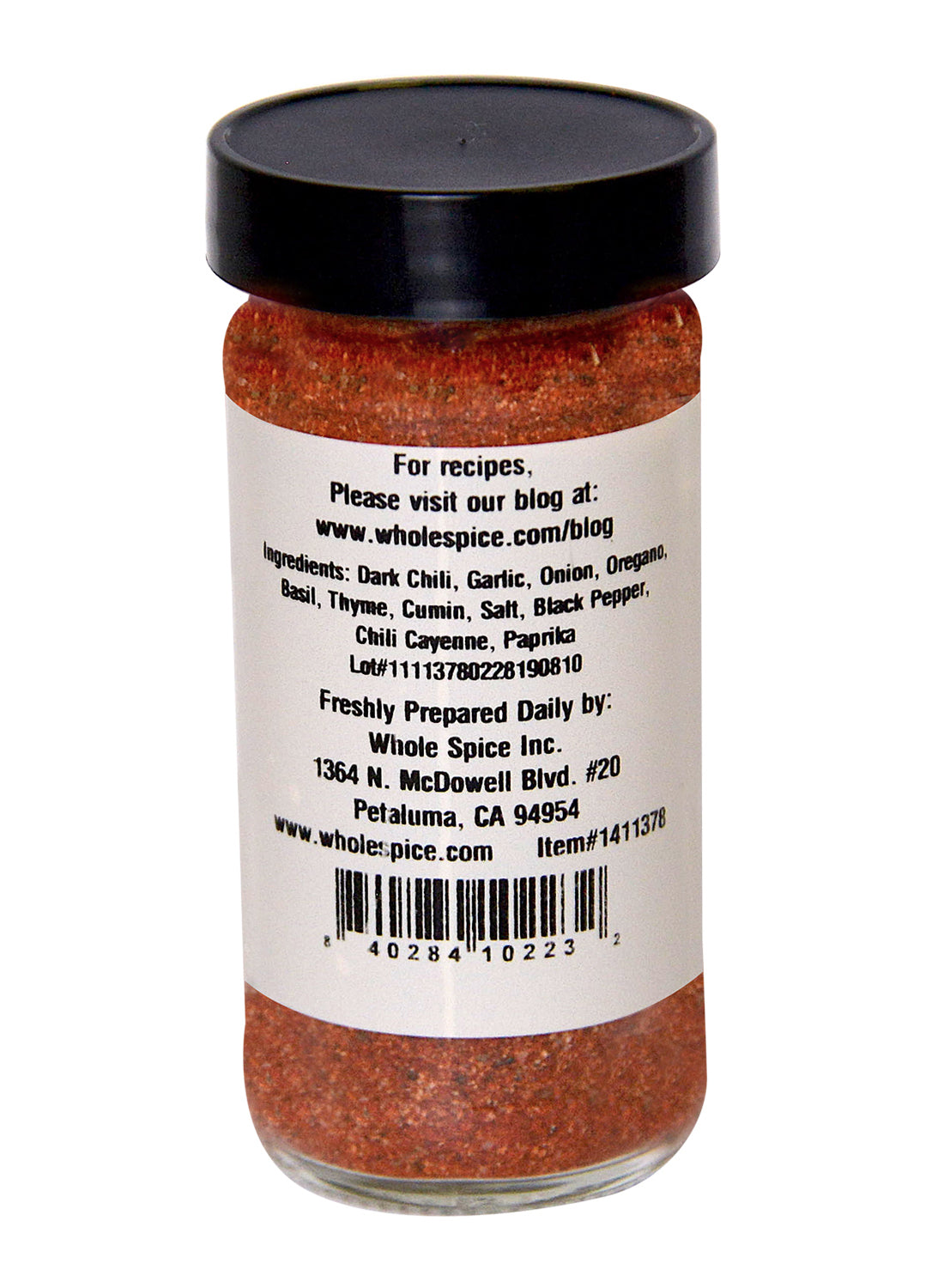 A clear spice jar with a white lid from Whole Spice Inc. contains vibrant red Blackened Seasoning. The label lists ingredients, company info, recipes like blackened salmon, website details, and displays Whole Spice Inc.'s barcode and address.