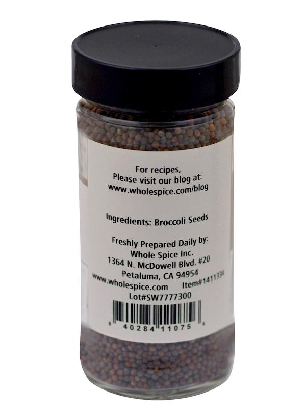 A clear jar labeled "Whole Spice Inc. Broccoli Seeds" displays small, dark seeds—ideal for adding a healthy crunch to salads. The white label features the brand's Petaluma, CA address, website, and a barcode.