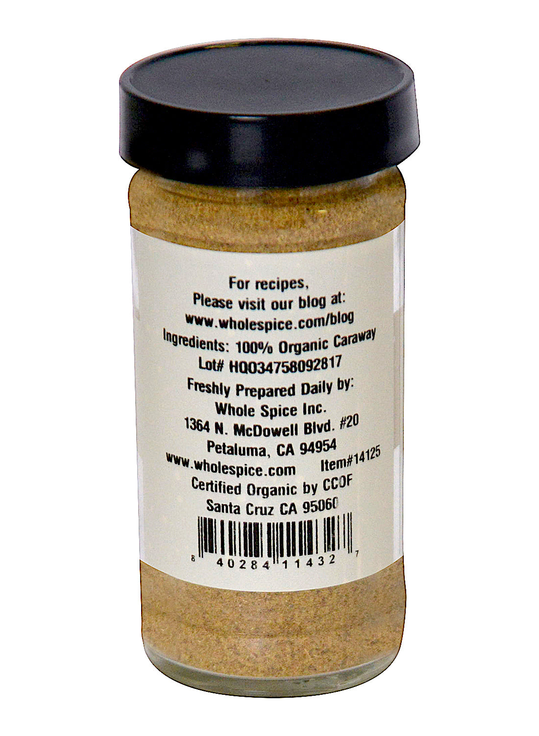 A glass jar of Caraway Seed Ground Organic from Whole Spice Inc. with a black lid features a back label listing ingredients, company info, barcode, address, website, lot number, and organic certification details.