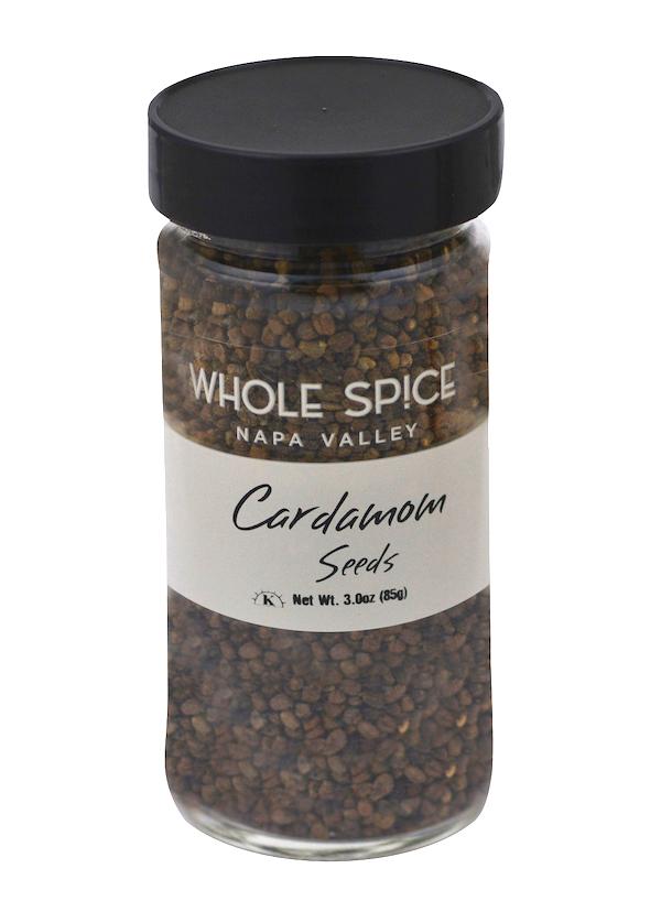 A clear glass jar with a black lid from Whole Spice Inc., labeled Cardamom Seeds, contains 3 oz (85g) of small brown seeds commonly used in Indian cuisine.