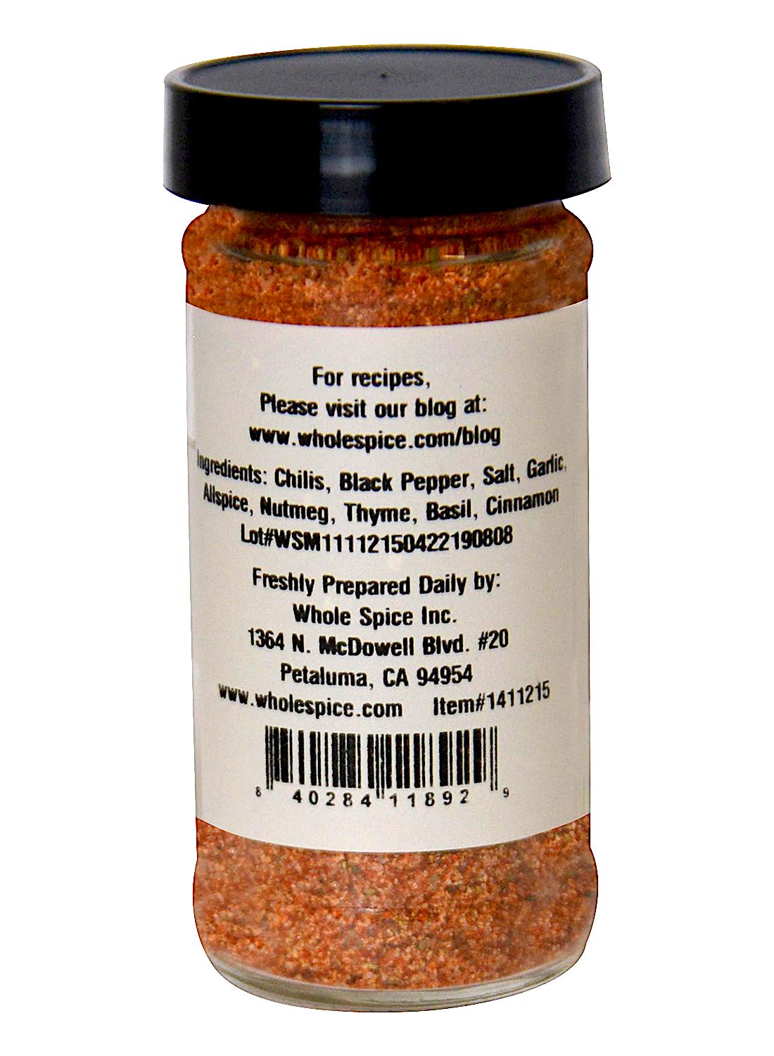 The Spicy Caribbean Chicken Rub by Whole Spice Inc. comes in a clear jar with a white label listing chilis, black pepper, salt, garlic, and herbs. Ideal for grilling or as a meat rub, the label includes prep tips, a website link, and barcode.
