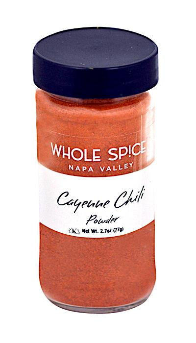 A clear glass jar with a dark blue lid contains vibrant Cayenne Chili Powder from Whole Spice Inc.—a hot chili spice that brings bold flavor to any dish.