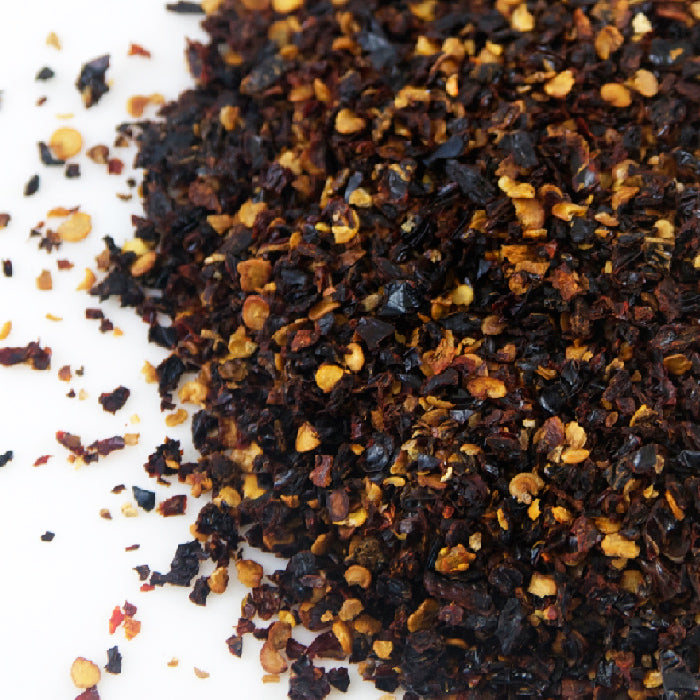 A pile of Chipotle Chili Crushed by Whole Spice Inc., made from smoked jalapeño peppers.