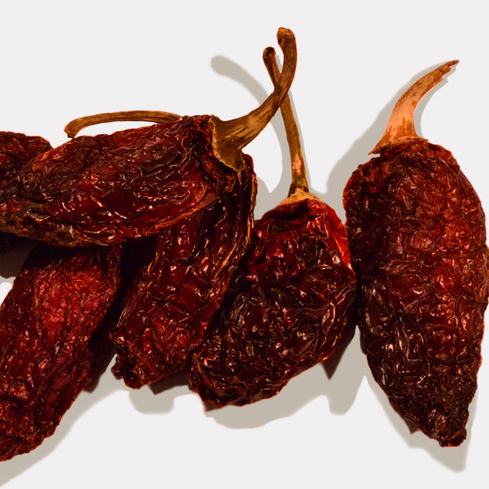 Four wrinkled Chipotle Chili Whole peppers from Whole Spice Inc., complete with stems, are arranged on a plain white background.