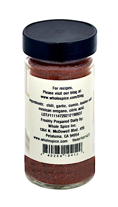 The Whole Spice Inc. Chili Seasoning comes in a clear jar with a black lid and features a label listing ingredients like chili, garlic, and cumin, plus company contact info and a website for chili recipes.