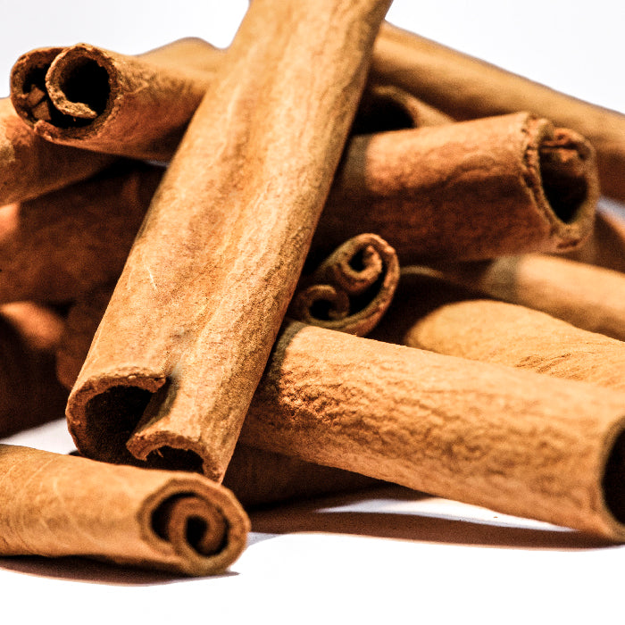 A close-up of several Whole Spice Inc. Cinnamon Sticks 4 inch, stacked and overlapping on a white background.