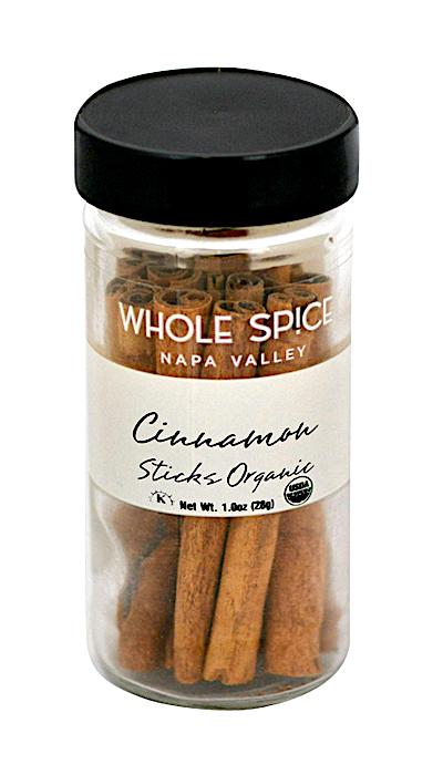 A clear glass jar with a black lid is labeled Whole Spice Inc. Cinnamon Sticks Organic. It contains several cinnamon sticks, weighs 1 oz (28g), and features the USDA organic seal.