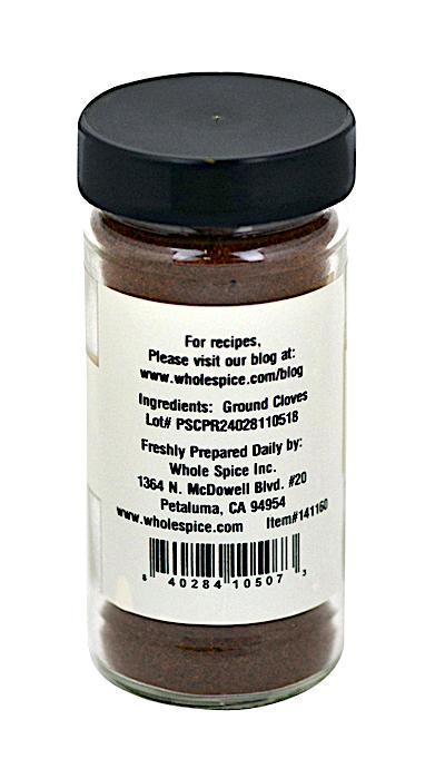 A glass jar with a black lid contains Cloves Ground from Whole Spice Inc. The label lists ingredients, supplier info (wholespice.com, Petaluma, CA), and a barcode at the bottom. This spice is popular for baking.