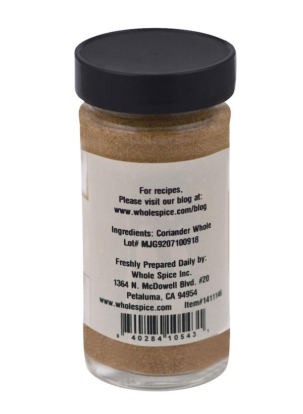 A spice jar with a black lid, labeled “Coriander Powder Toasted,” displays premium details and ingredients, the Whole Spice Inc. address in Petaluma, CA, and a barcode at the bottom—ideal for coriander lovers.