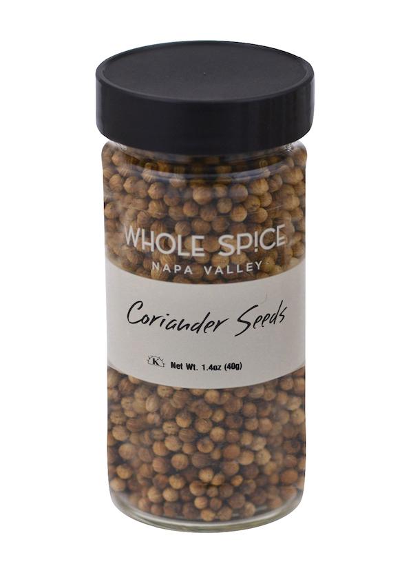 A clear glass jar with a black lid holds Coriander Seeds by Whole Spice Inc., ideal for Thai curries or pickling. The label states a net weight of 1.4 oz (40g).