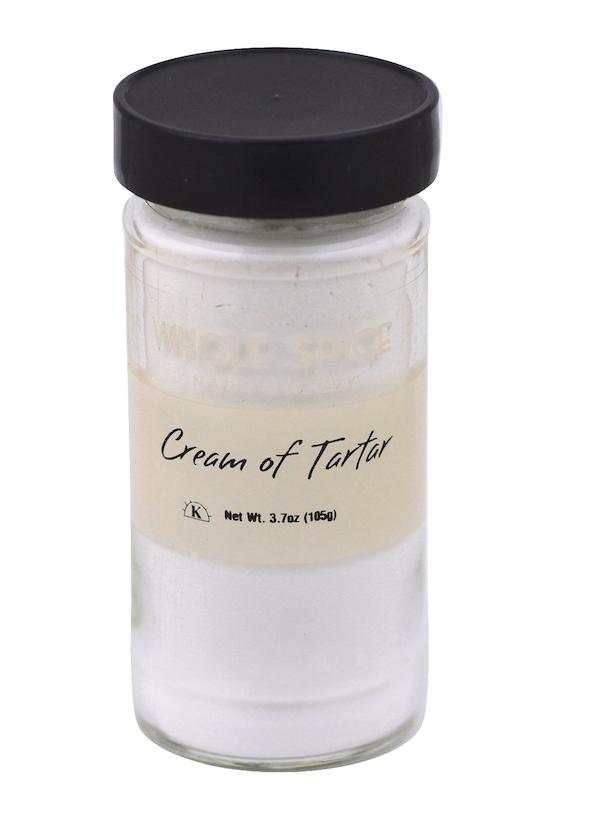 A clear glass jar with a black lid from Whole Spice Inc., labeled Cream of Tartar, holds 3.7 oz (105 g) of white powder—an essential baking ingredient for stabilizing egg whites in your recipes.