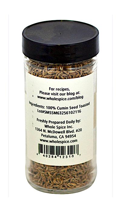 A clear spice jar with a black lid, filled with Cumin Seed Whole Toasted from Whole Spice Inc. The label lists ingredients, company info, and an address, plus a barcode—ideal for any cumin seed or spice enthusiast.