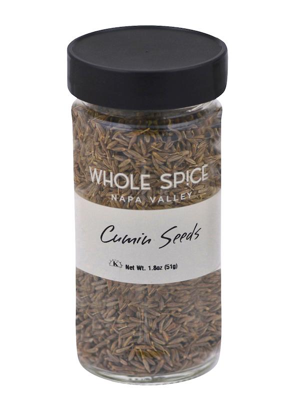 A clear glass jar with a black lid, filled with cumin seeds from Whole Spice Inc., is perfect for savory dishes. The label reads "Cumin Seeds" and indicates a net weight of 1.8 oz (51g).