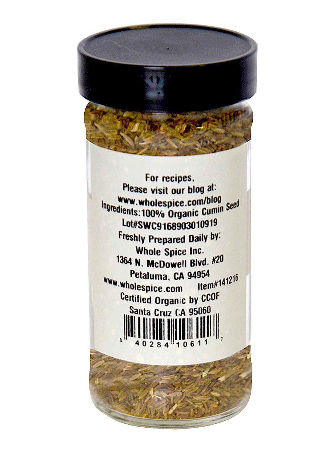 A clear spice jar labeled "Cumin Seeds Organic" by Whole Spice Inc., a key garam masala ingredient, displays ingredients, manufacturer info, and a barcode. The jar is filled with light brown cumin seeds.