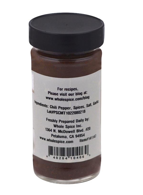A Whole Spice Inc. Dark Chili Powder jar with a black lid features a label listing chili powder, spices, salt, and garlic as ingredients, plus company info and a barcode at the bottom.