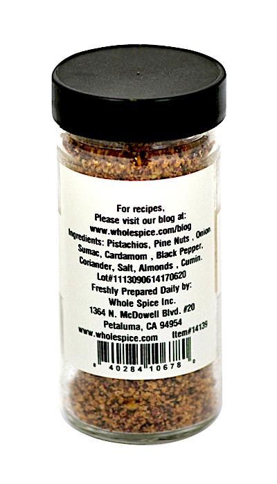 A clear spice jar with a black lid features a printed label with ingredients, company info, and barcode. Druze Nuts & Spice Mix by Whole Spice Inc. blends pistachios, pine nuts, sumac, cardamom, and more for authentic Middle Eastern flavor.