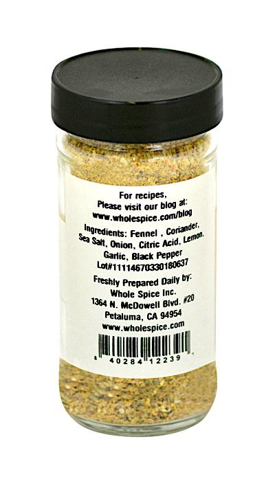 A clear spice jar from Whole Spice Inc. with a white label lists ingredients and company info. Contains fennel and fragrant fennel pollen, ideal as a Fennel Rub for roasted fish. Prepared by Whole Spice Inc., Petaluma, CA.