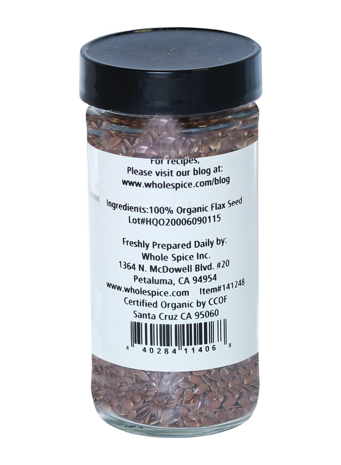 A clear glass jar of Flax Seeds Organic by Whole Spice Inc., featuring a white back label with heart-healthy ingredient info, company details, website, address, and organic certification.