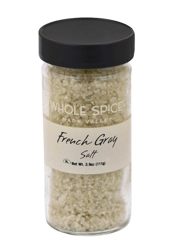 A clear glass jar with a black lid contains coarse French Gray Salt by Whole Spice Inc., Net Wt. 3.9oz (111g), ideal as a finishing salt.