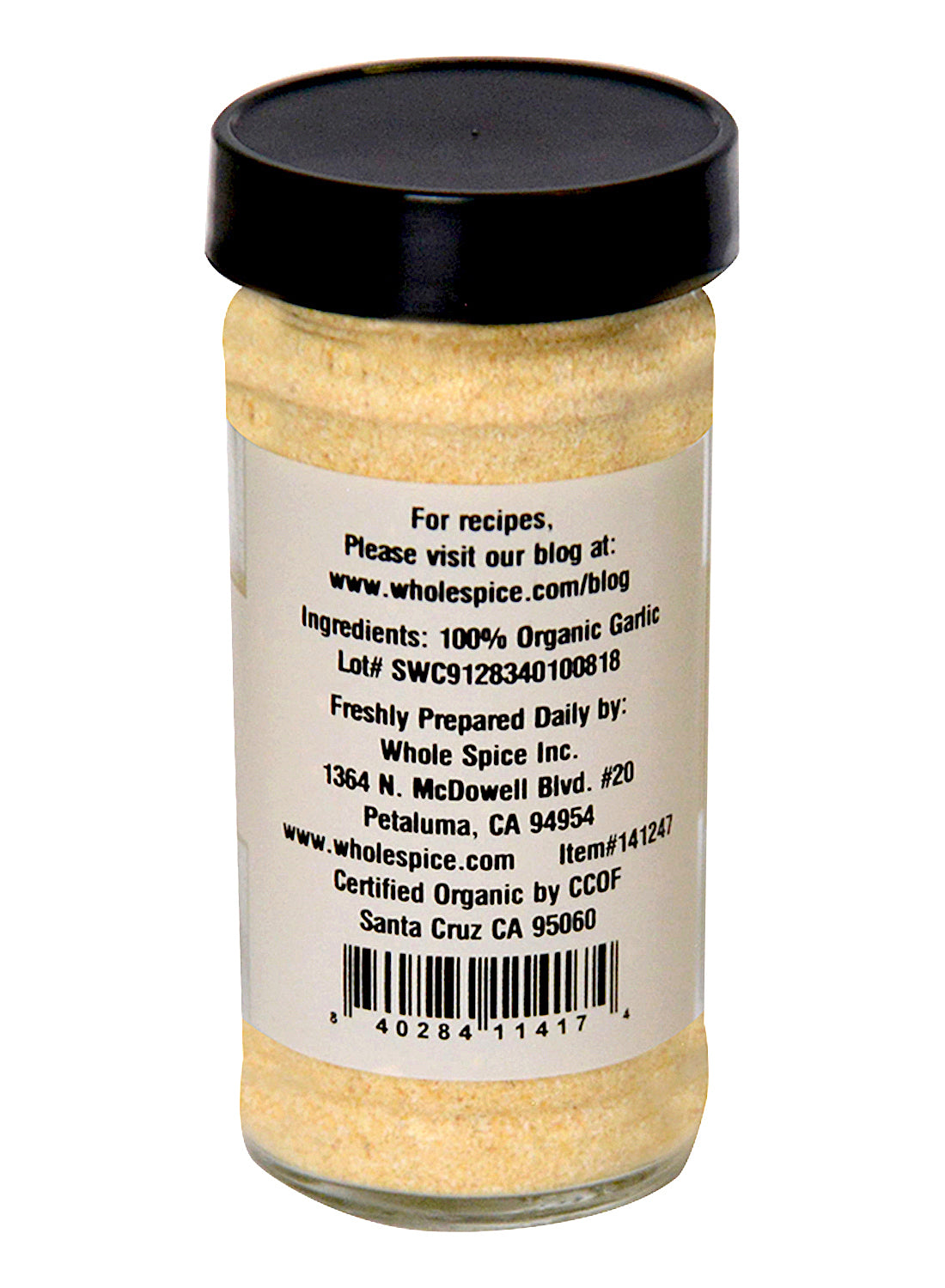 A clear spice jar with a black lid holds light beige Garlic Granulated Organic powder by Whole Spice Inc. The label shows 100% organic garlic, company contact info, recipe website, and a barcode at the bottom.