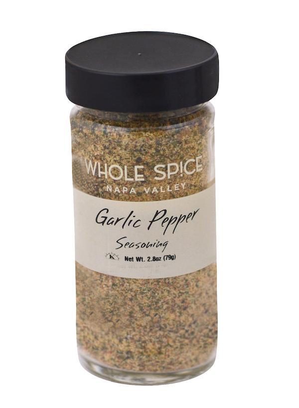 A clear glass jar with a black lid labeled Whole Spice Inc. Garlic Pepper Seasoning, Net Wt. 2.8oz (79g), contains a coarse, multicolored blend that’s perfect as a flavorful seasoning for meats.
